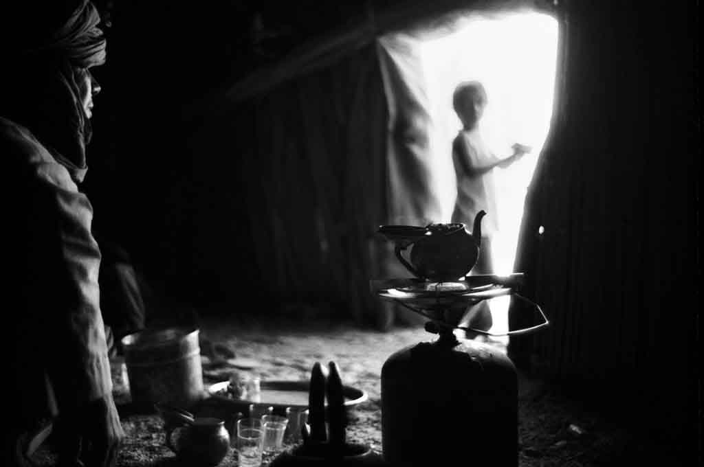 Dans le village de Taroumout, à 40 km de Tamanrasset, c'est l'heure du thé. Les trois verres de thé - amer, peu sucré, sucré - sont pris dans l'après-midi lorsque la chaleur a un peu diminué. Tassili du Hoggar, Sahara algérien, 1993