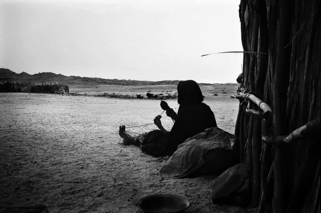 A la fraîche dans le village de Touaregs sédentaires dEzarnen, une vieille femme file des poils de chèvre. Tassili n'Ajjers, Sahara algérien, 1993
